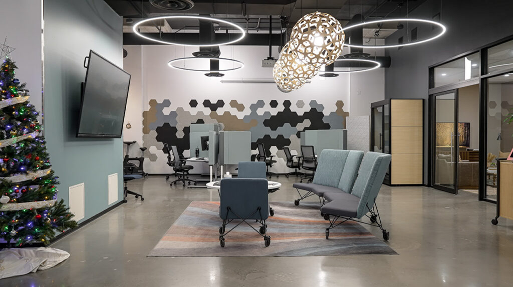 Open, modern office lounge with circular pendant lights, a Christmas tree, and teal modular seating around a rug.