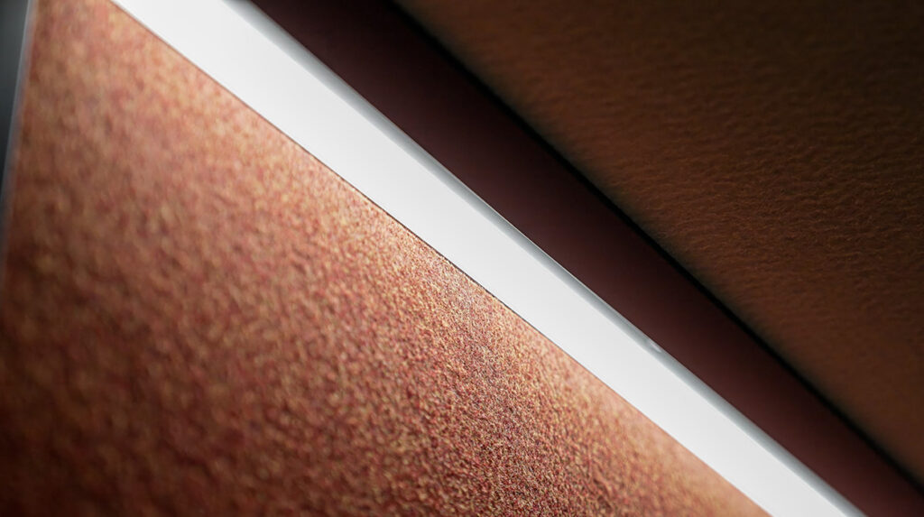 Close-up of a white fluorescent light tube mounted diagonally across a textured brown wall.