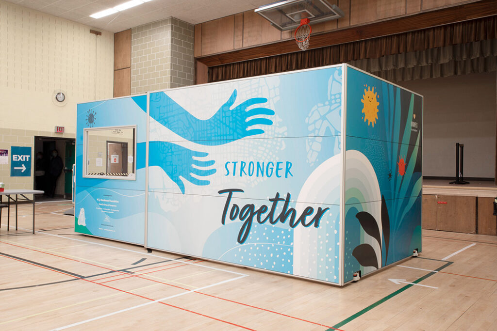 Modular display panels in a gymnasium with a blue mural reading "Stronger Together" and a large hand graphic across the panels.